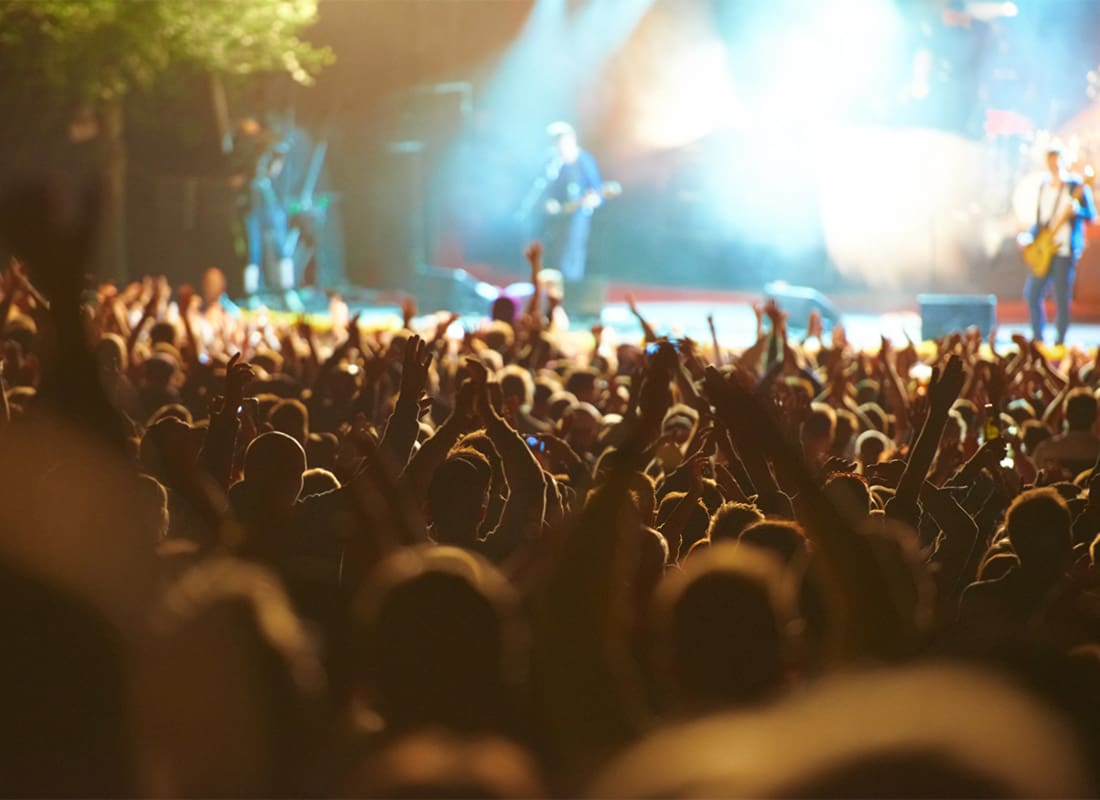 Event Insurance - View of a Large Crowd of Cheering People During a Concert with a Band on the Front Stage