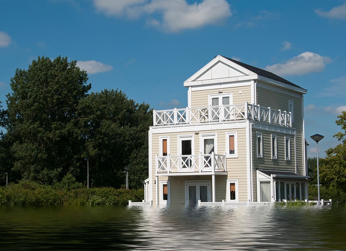 Flood Insurance - Exterior View of a Wooden Three Story Home Next to Green Trees After a Flood
